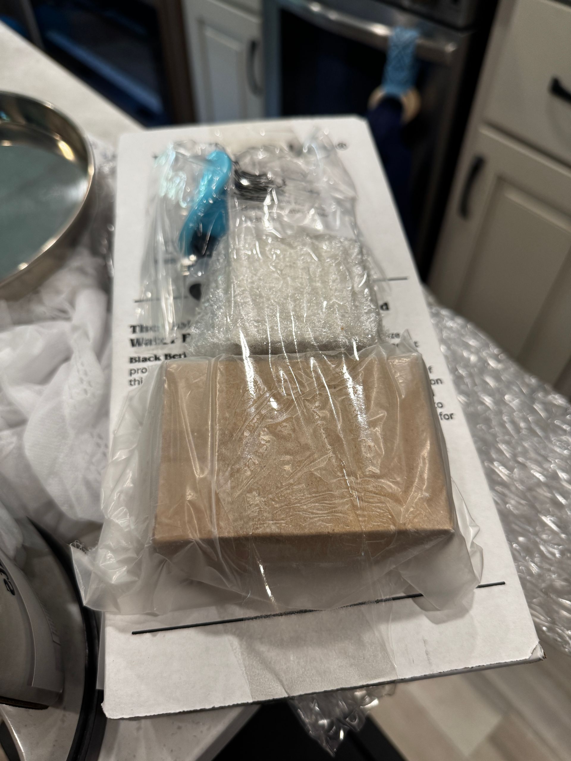 A package with a wooden block and accessories inside a plastic wrapper on a counter.