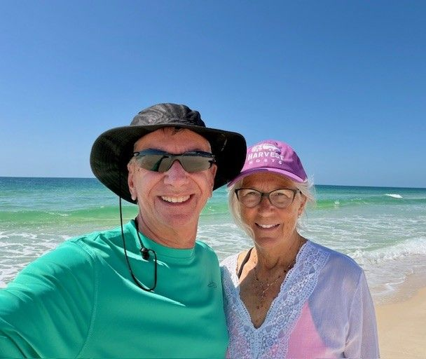 Woman smiling under canopy of colorful umbrellas, outdoor setting.