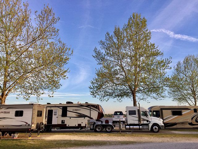 A rv is being towed by a semi truck in a parking lot.