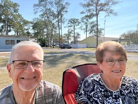A woman wearing a red top and black cardigan and earrings is smiling for the camera.