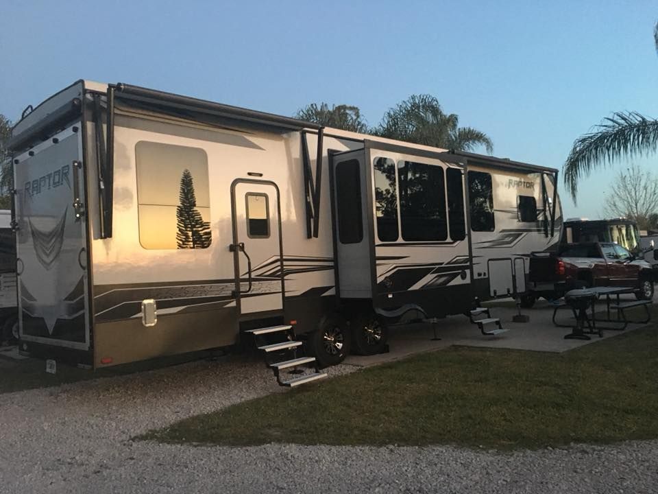 A rv is parked in a gravel lot next to a picnic table.
