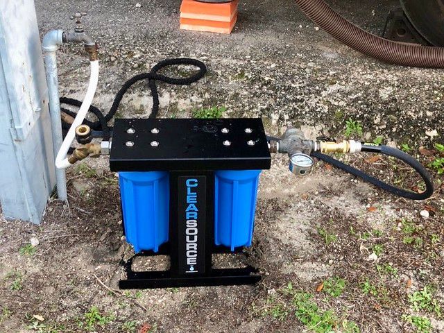 A blue water filter is sitting on the ground next to a hose