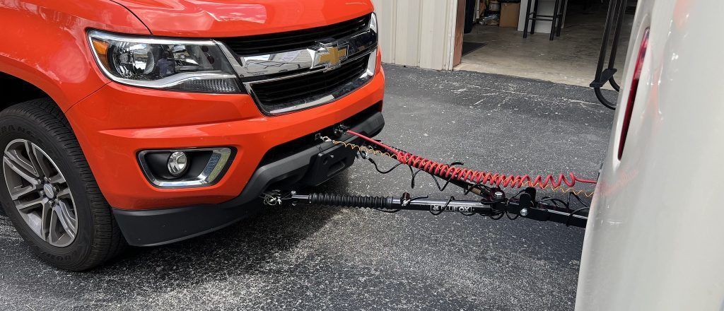A red truck is towing a trailer in a garage.