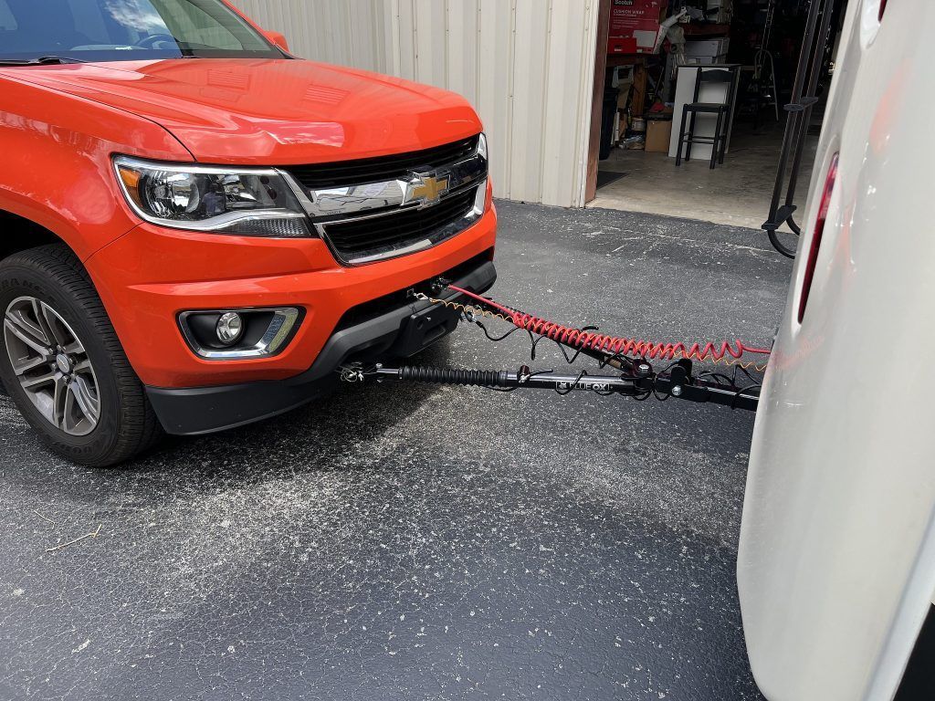 A red truck is towing a white trailer.