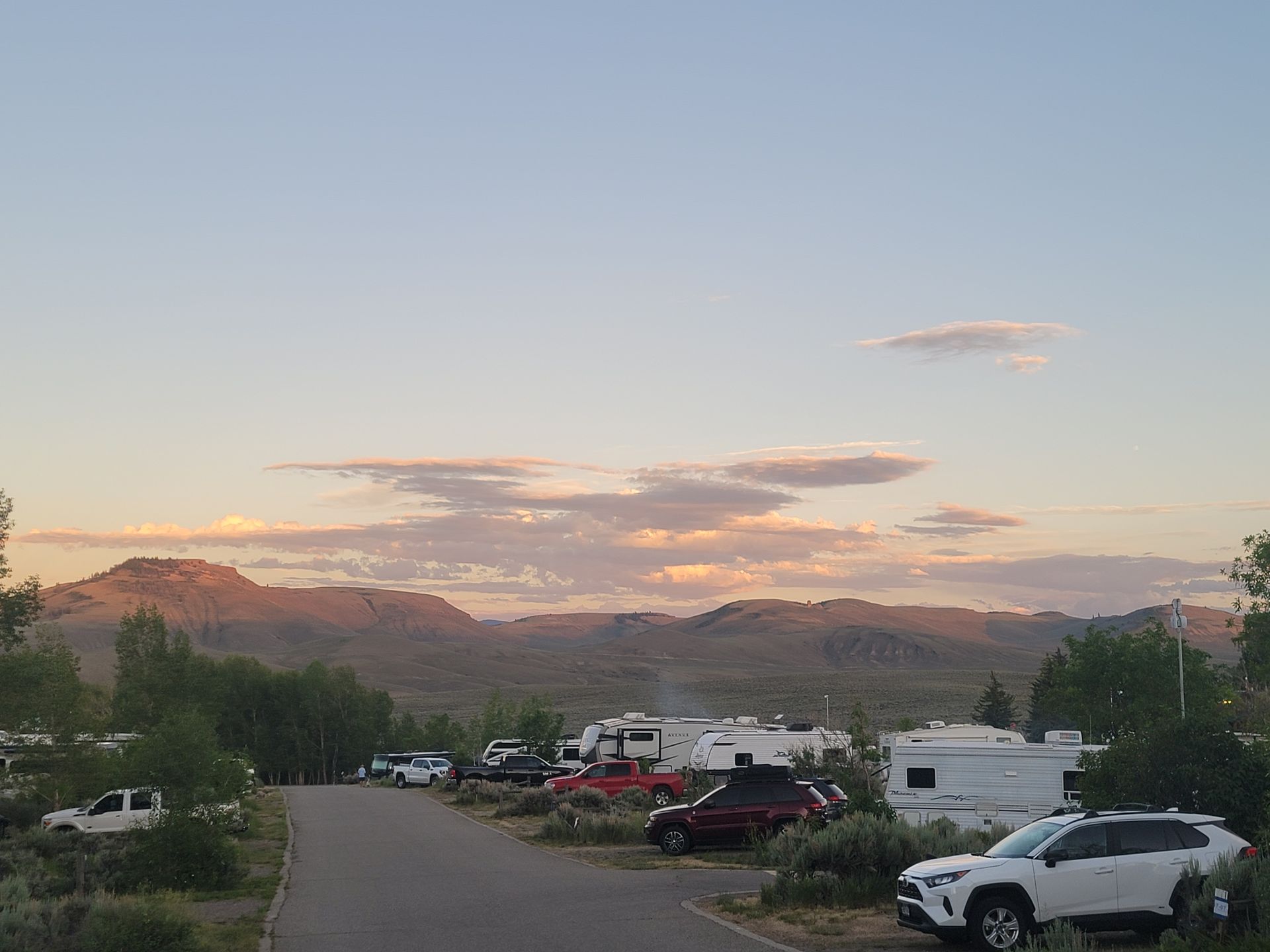 A lot of cars are parked in a parking lot with mountains in the background.