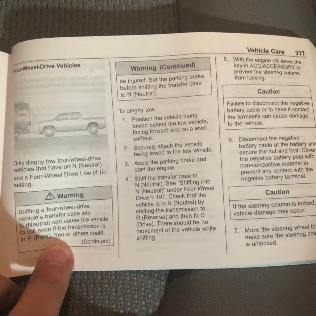 A person is holding a manual with a picture of a truck on it