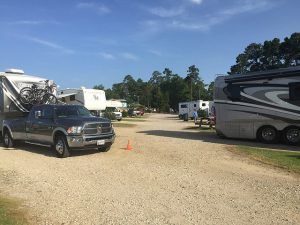 A truck is parked in a gravel lot next to a rv.