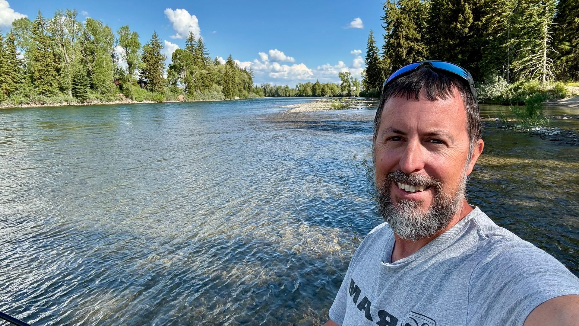 A woman wearing a black tank top and earrings is smiling for the camera.