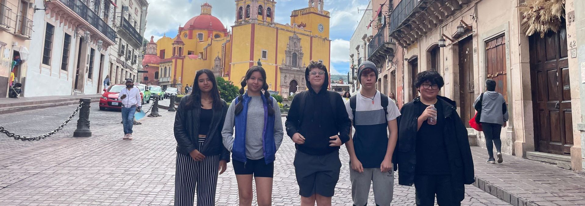 A group of people are standing on a cobblestone street in front of a church.