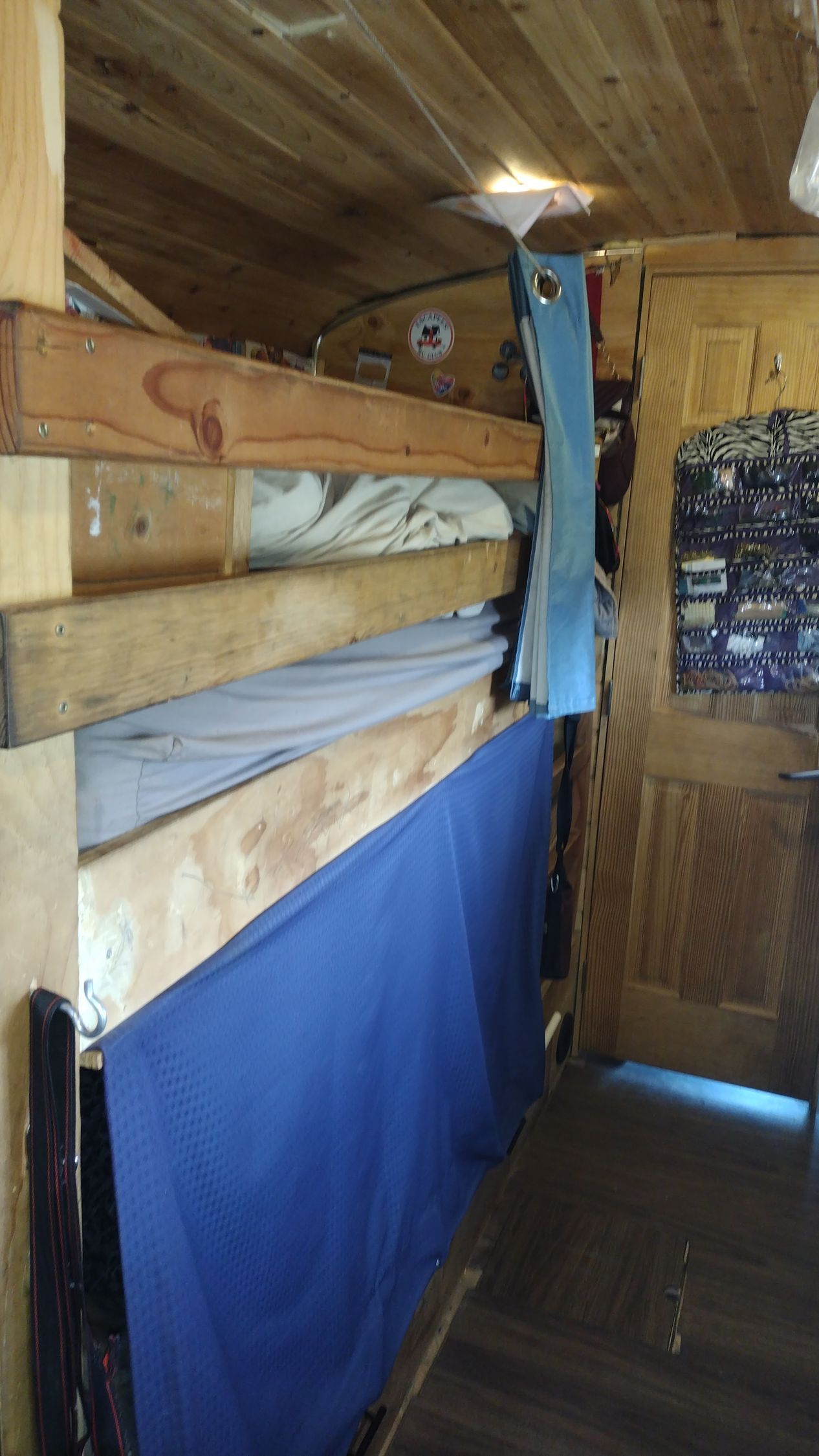 A bunk bed with a blue mattress in a wooden room.
