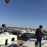 A man and a child are standing on top of a roof watching a hot air balloon.