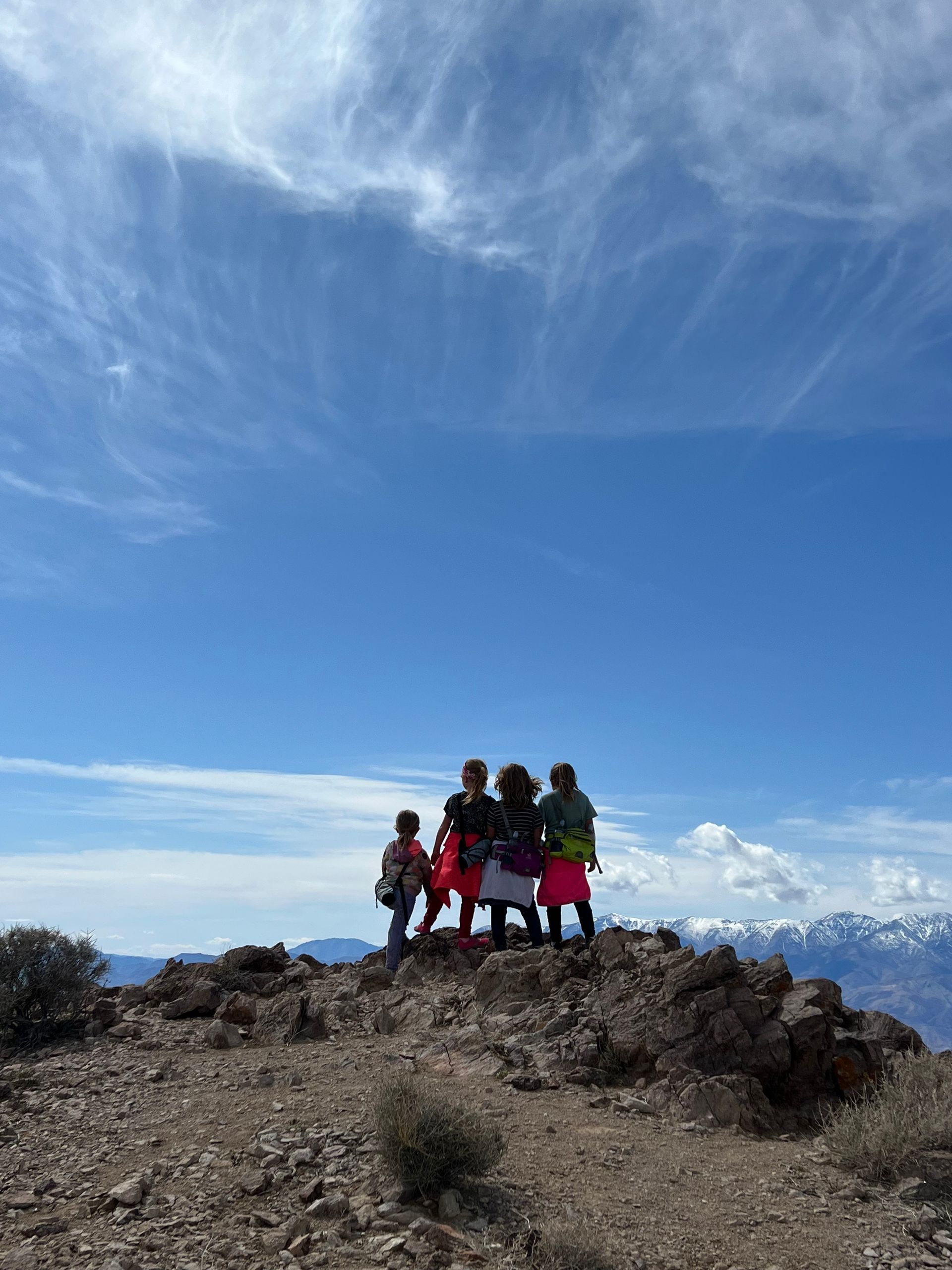 A group of people are standing on top of a rocky hill.