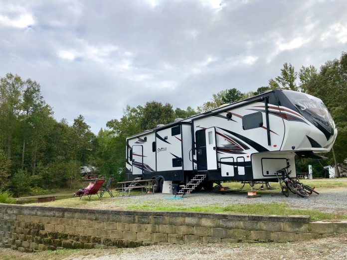 A large white and black rv is parked in a gravel lot.