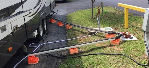 A rv is plugged into a power outlet in a parking lot.