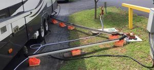 A rv is plugged into a power outlet in a parking lot.