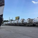 A row of rvs are parked in a parking lot.