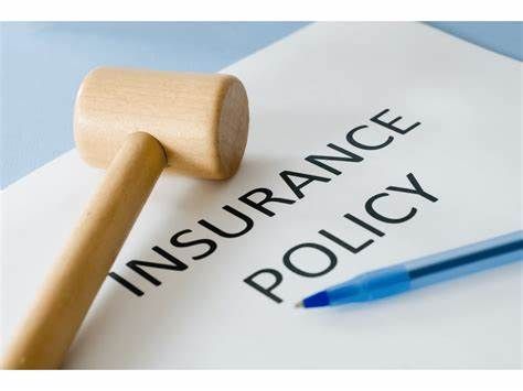 A wooden hammer is sitting on top of a piece of paper that says insurance policy.