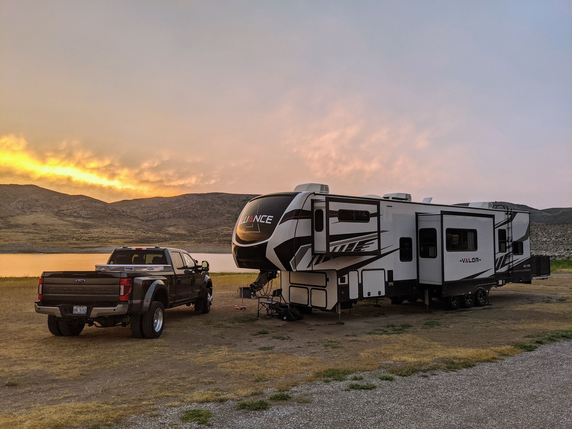 A truck is parked next to a rv at sunset.