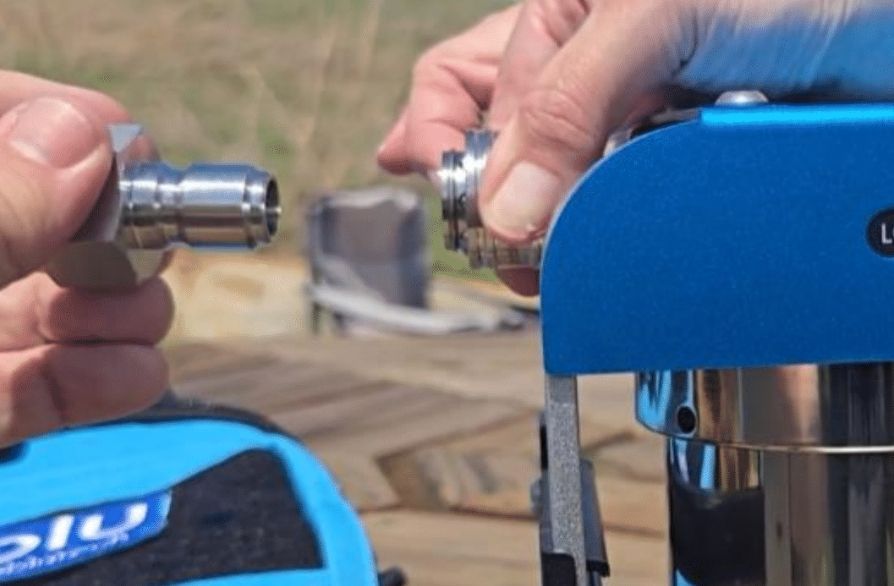 A person's hands connecting a silver metal hose fitting to a blue portable water filtration device.