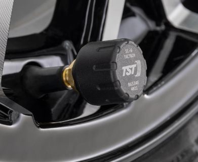 Close-up of a black tire pressure sensor mounted on a wheel rim.