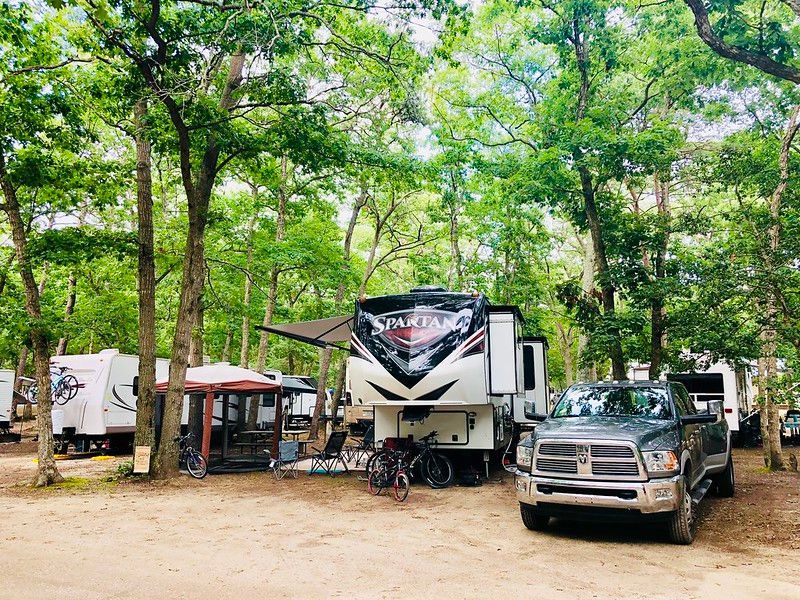 A truck is parked in front of a rv in a campground.