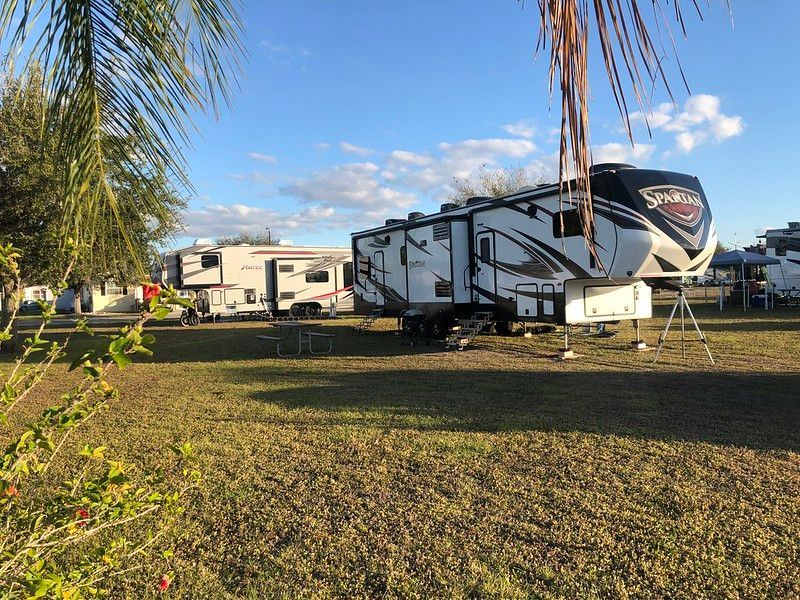 A row of rvs are parked in a grassy field.
