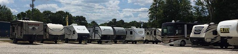 A row of rvs are parked in a parking lot.