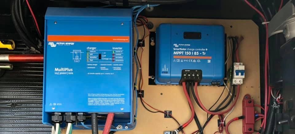 A blue inverter and a solar charge controller are sitting on top of a wooden board.