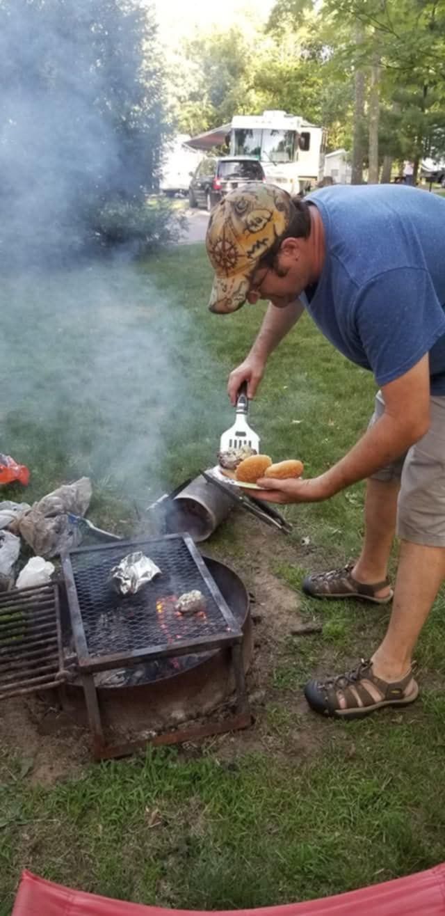 A man is cooking food over a fire pit.