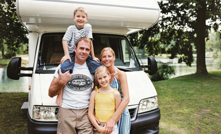 A family is standing in front of a camper van.