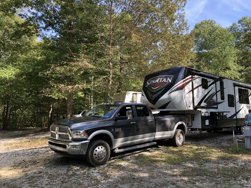 A truck is towing a rv in a parking lot.