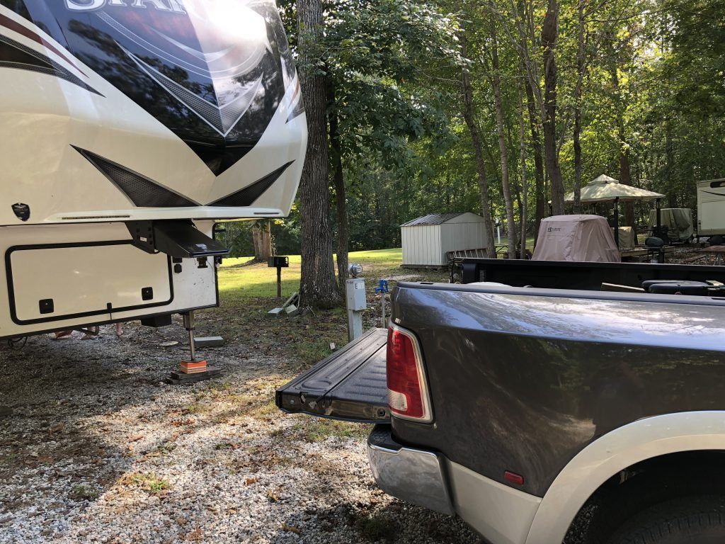 A truck is parked next to a rv at a campground.