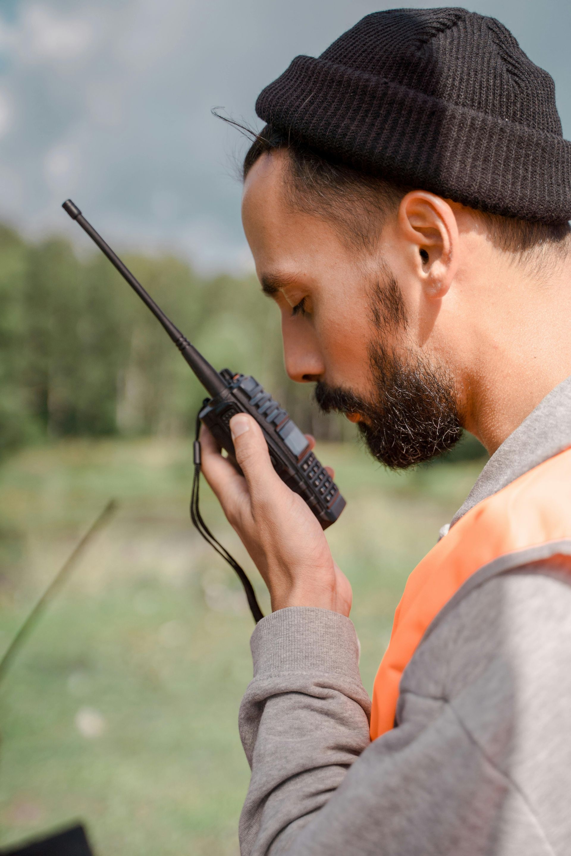 A man is talking on a walkie talkie in a field.