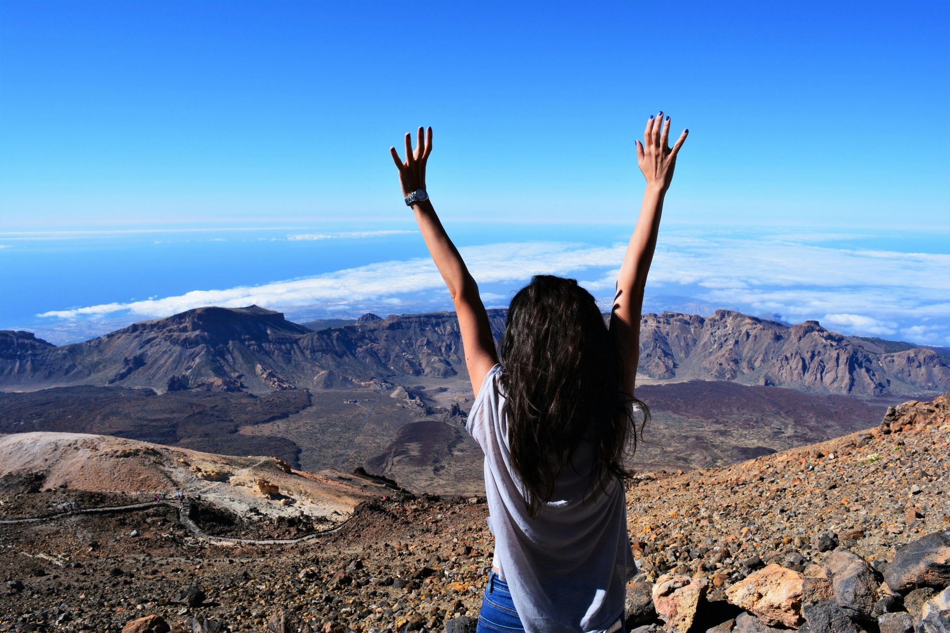 A woman is standing on top of a mountain with her arms in the air.