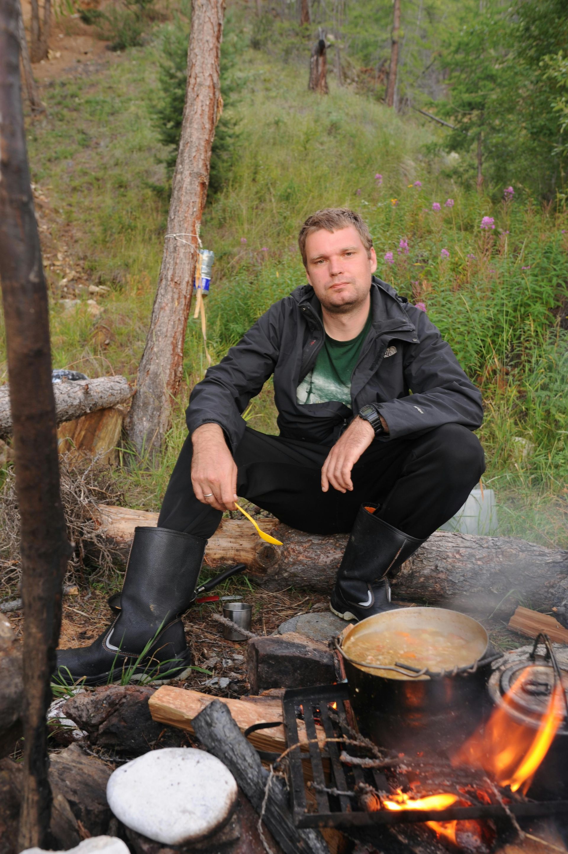 A man is standing in the woods holding a camera.