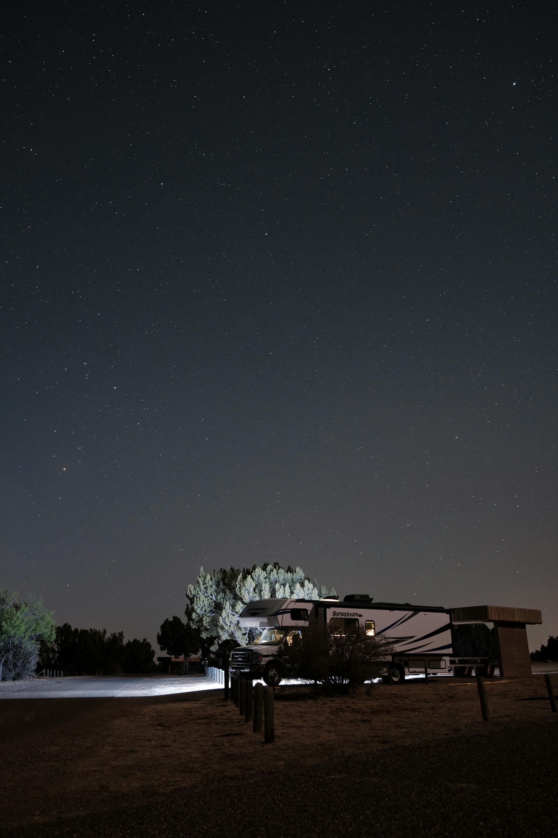 A night sky filled with lots of stars and a fence in the foreground.
