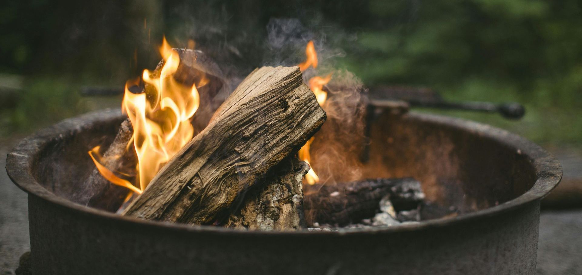 A fire pit filled with logs is being lit up.