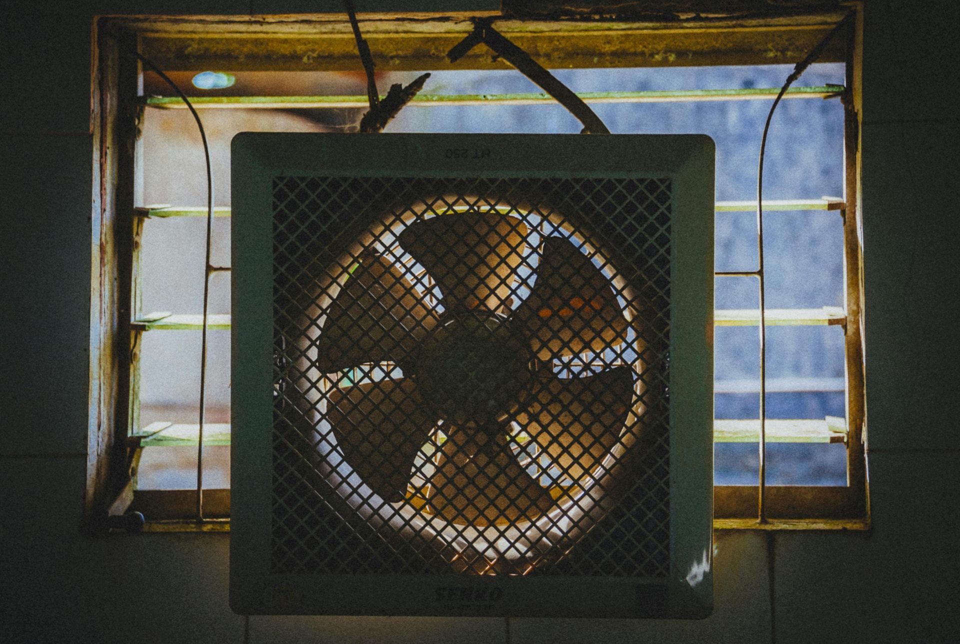 A fan is hanging from the ceiling next to a window