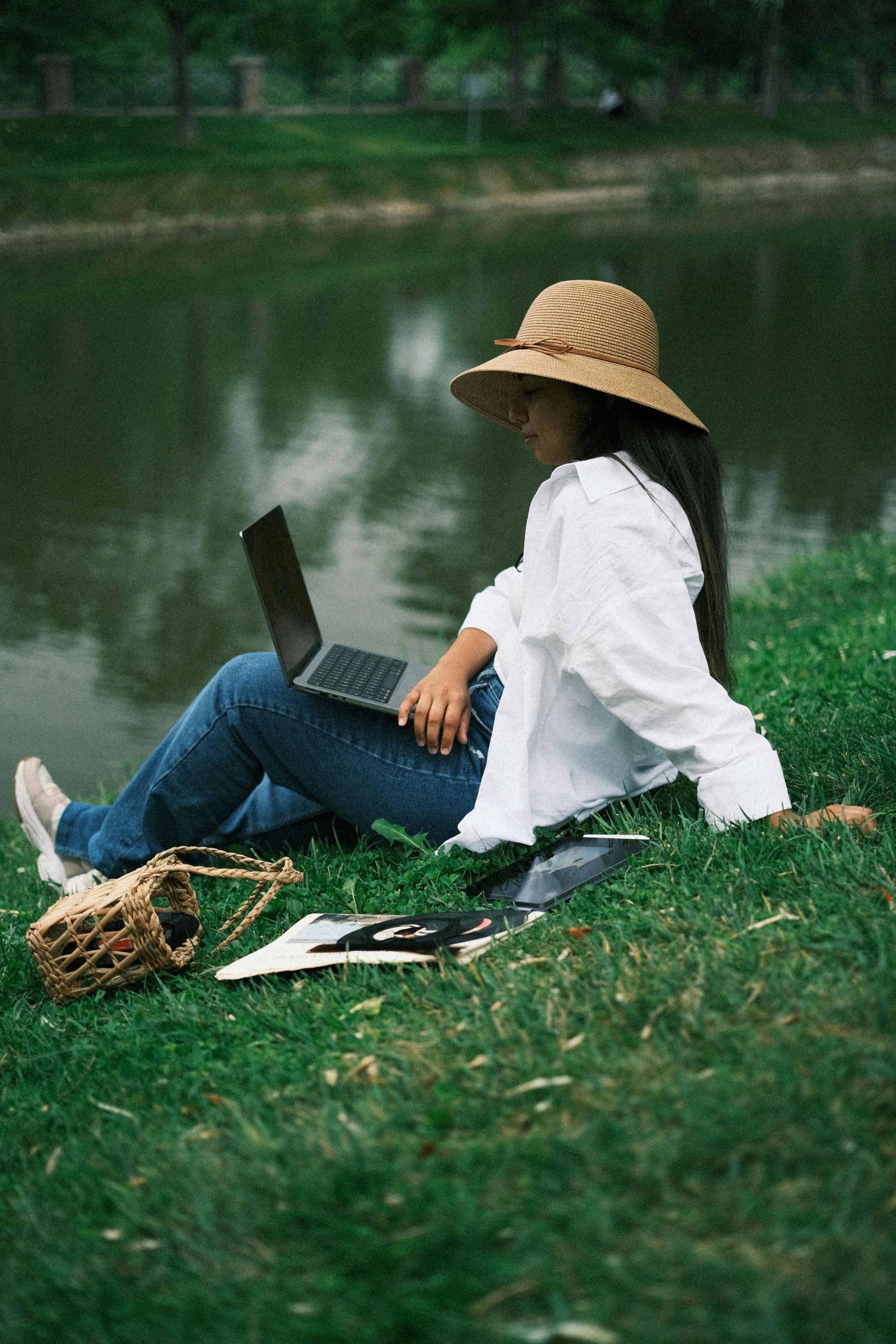 A woman is sitting on the grass using a laptop computer.