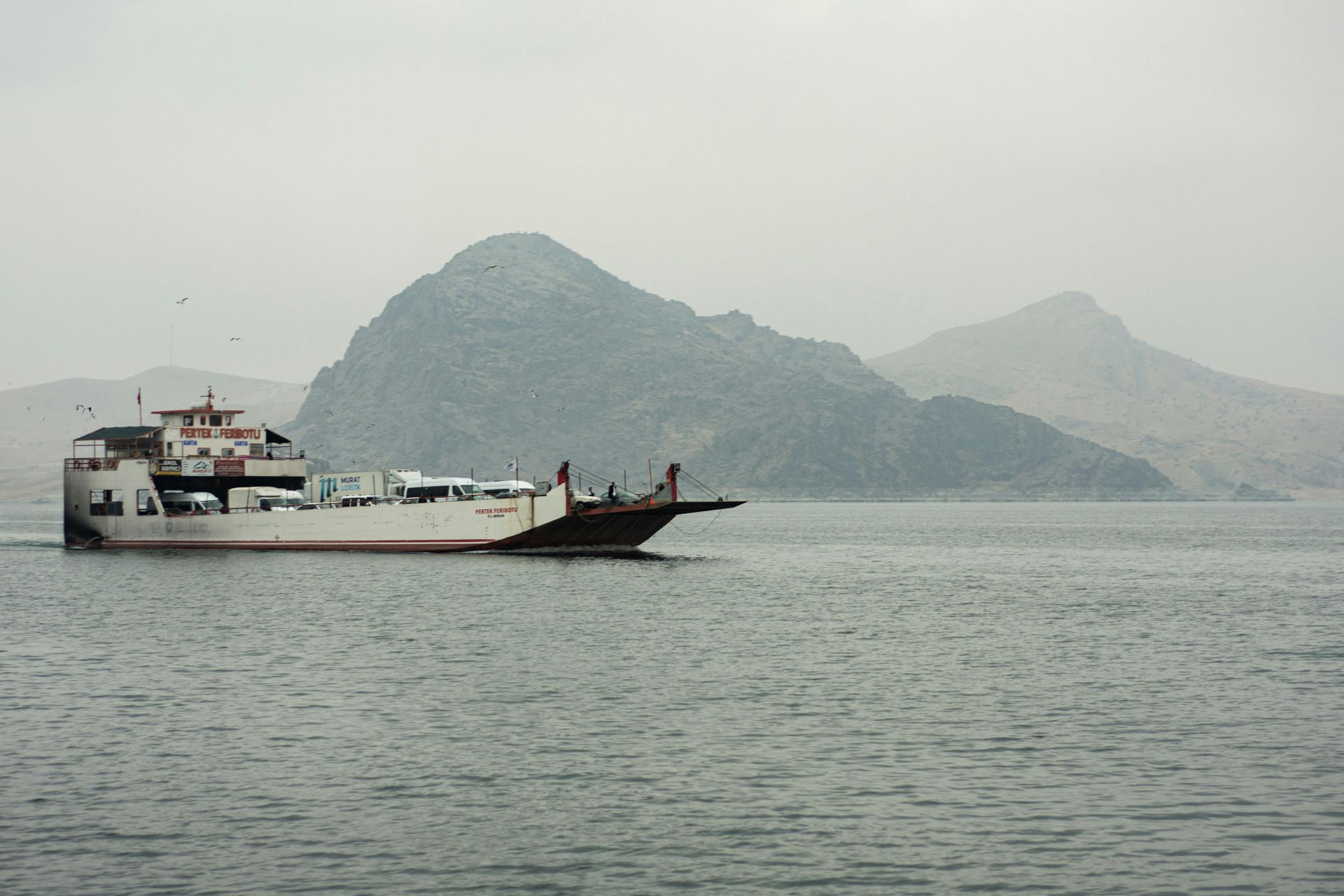 Cargo ferry on calm water with misty mountains in the background