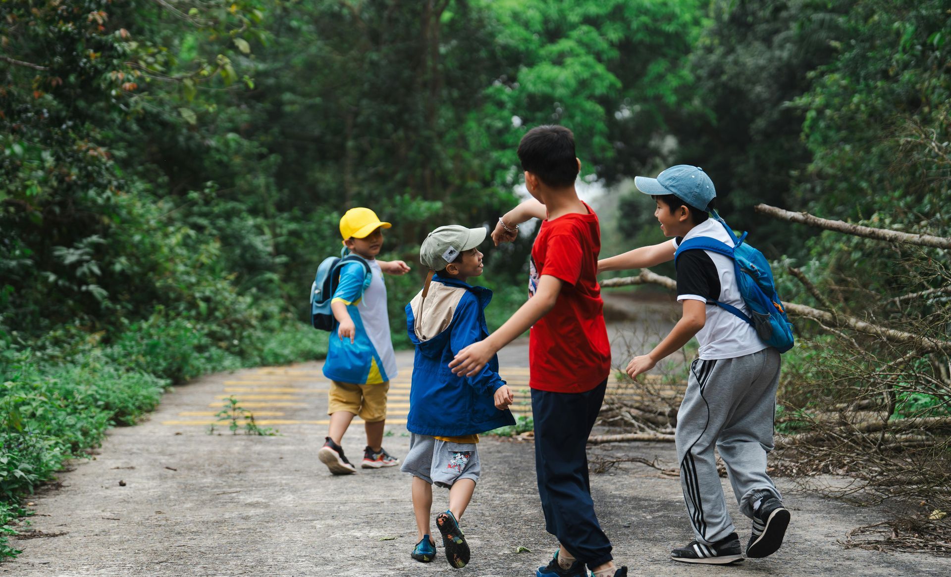 A group of young boys are walking down a path in the woods.