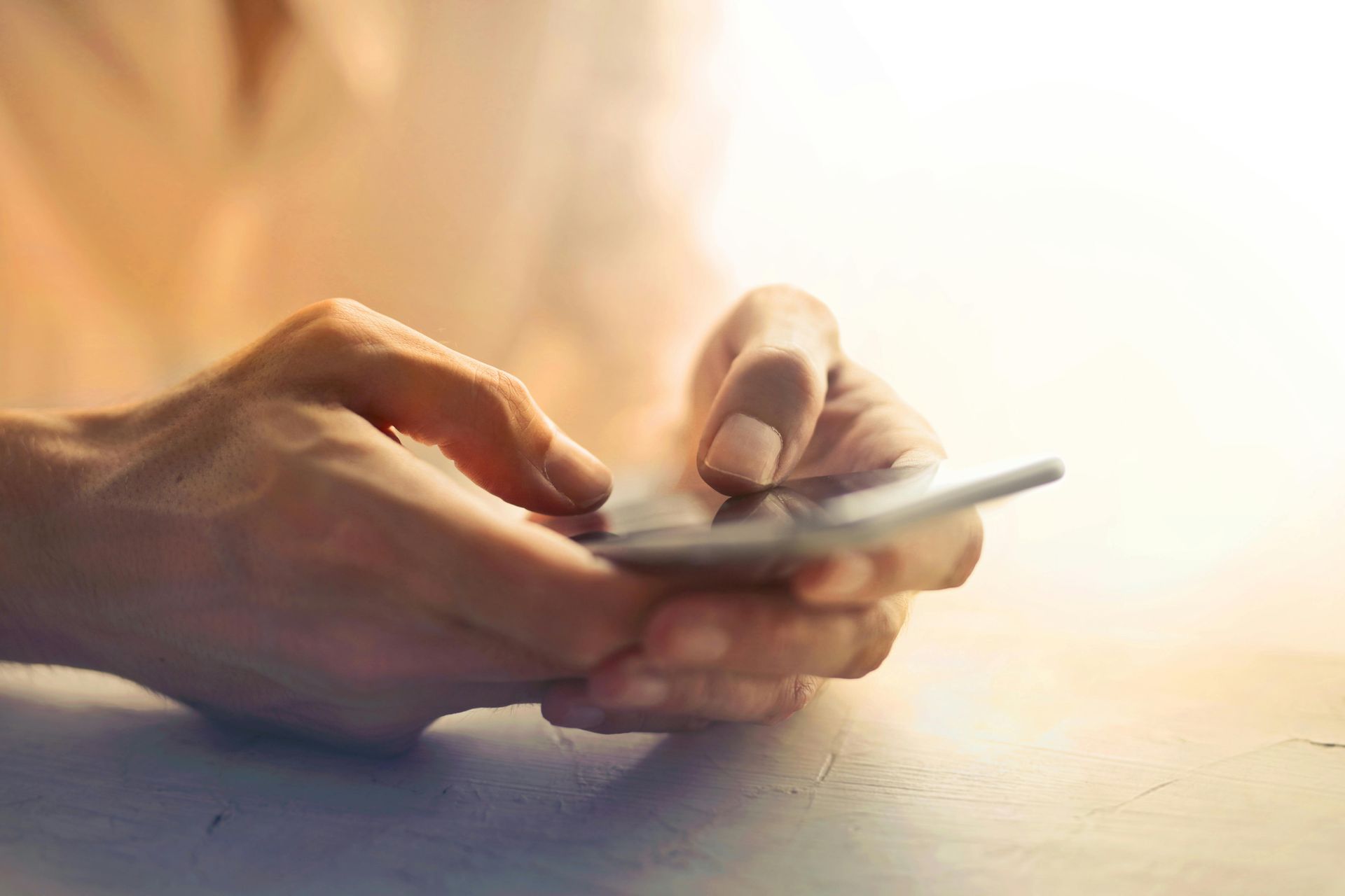 A person is using a cell phone on a table.