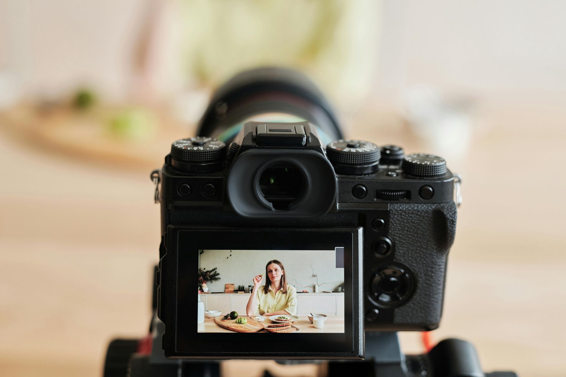 A camera is taking a picture of a woman sitting at a table.