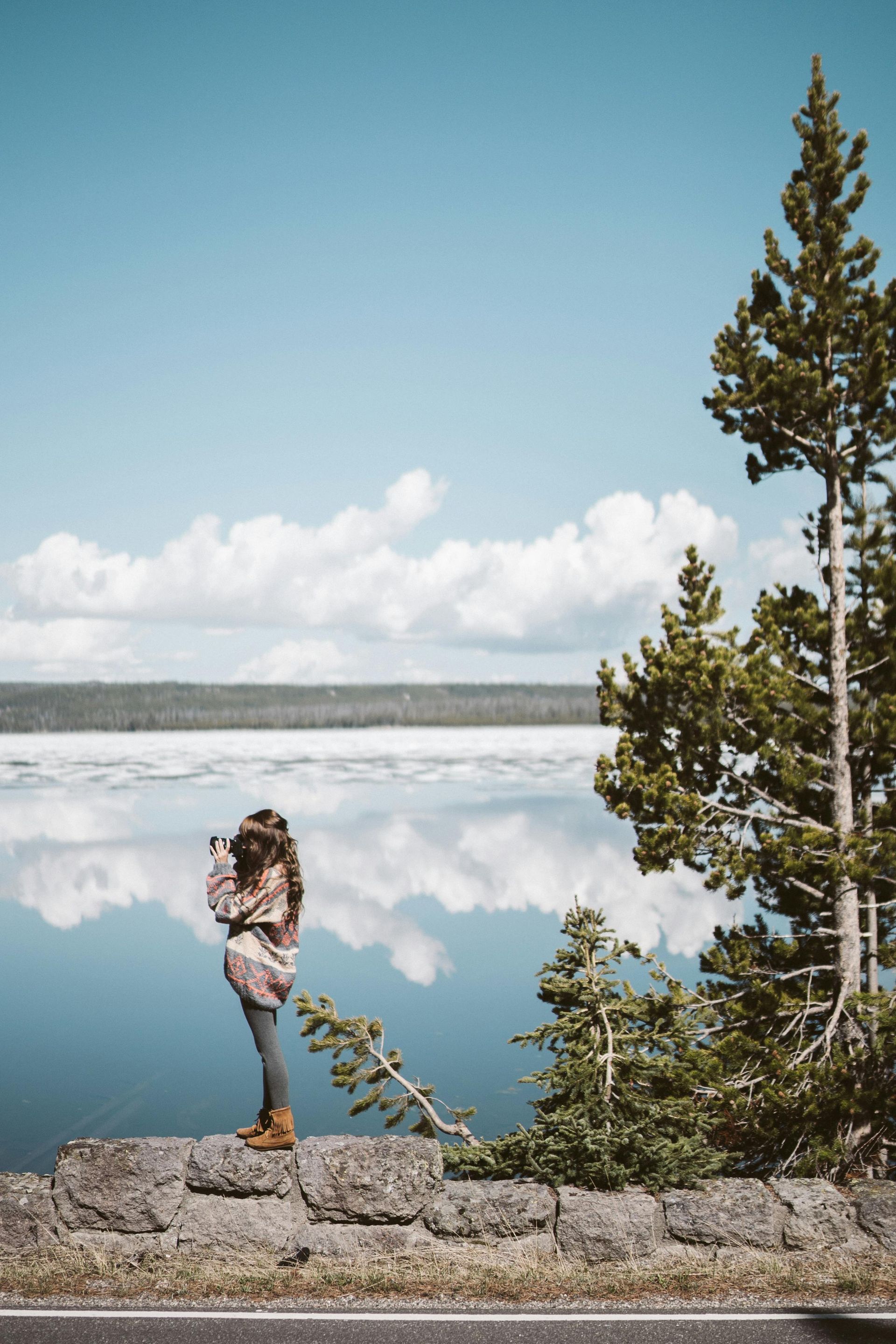 A woman is standing on a rock overlooking a lake.