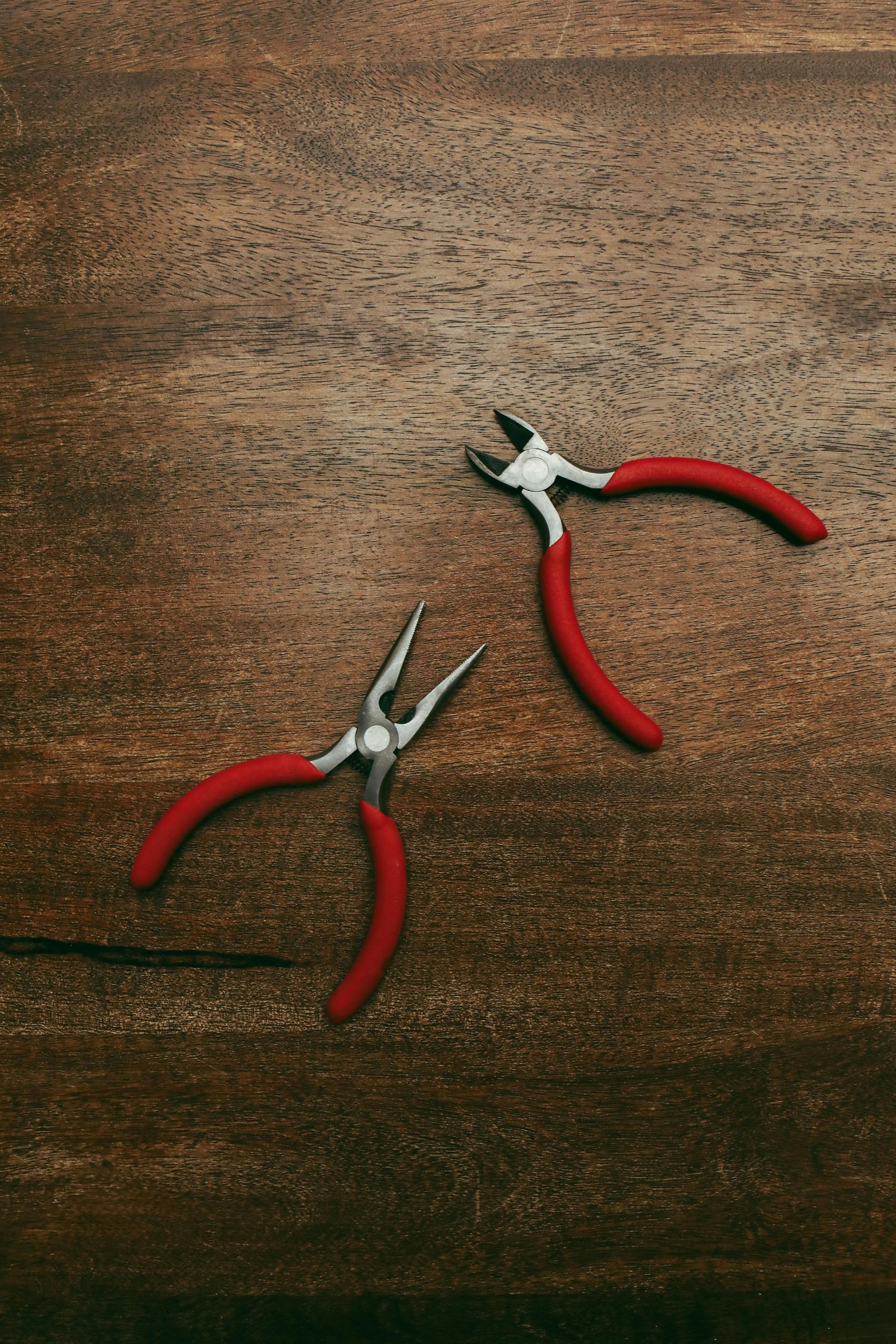 Two pliers are sitting on a wooden table.