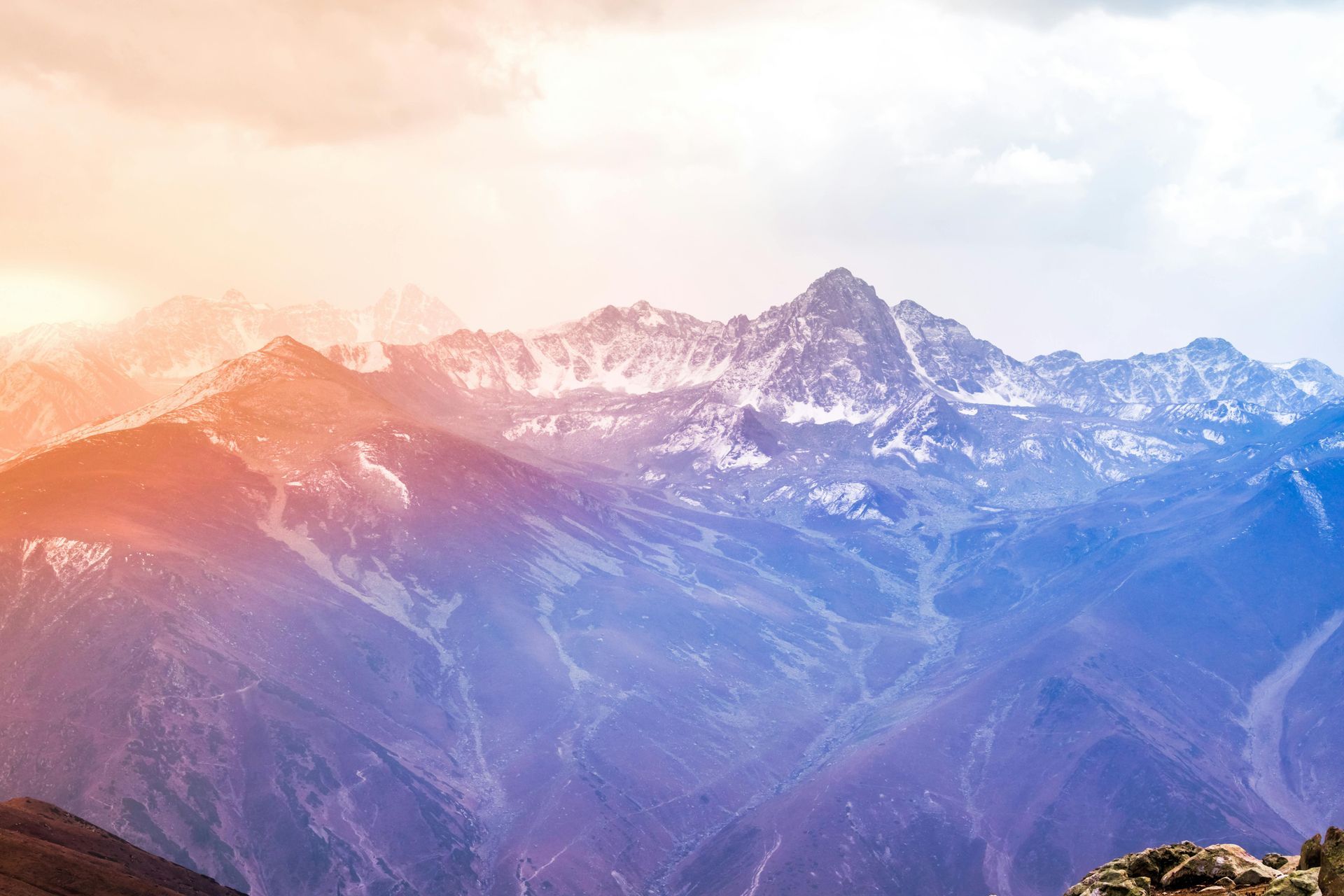 A view of a snowy mountain range at sunset.