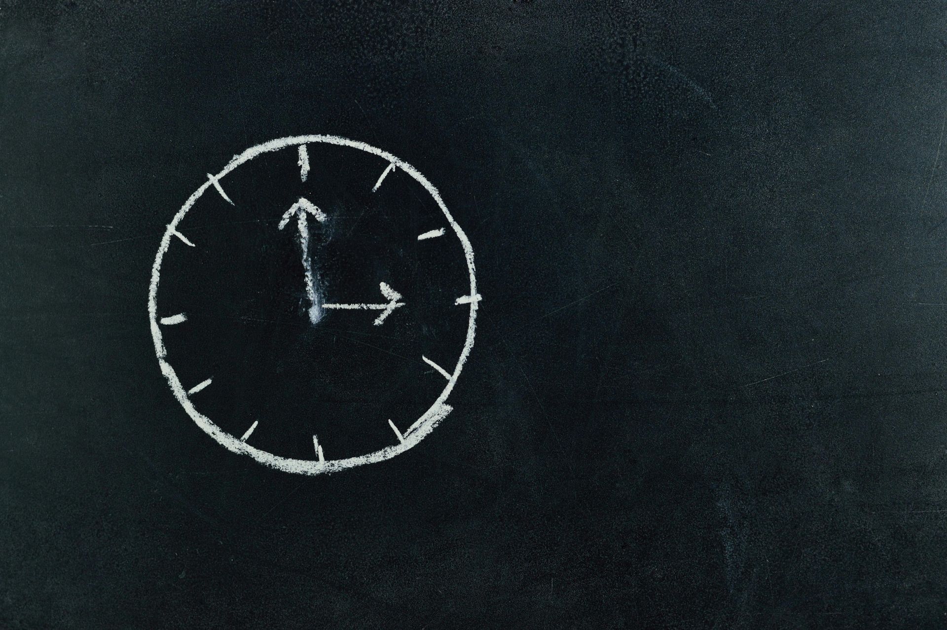 A chalk drawing of a clock on a blackboard