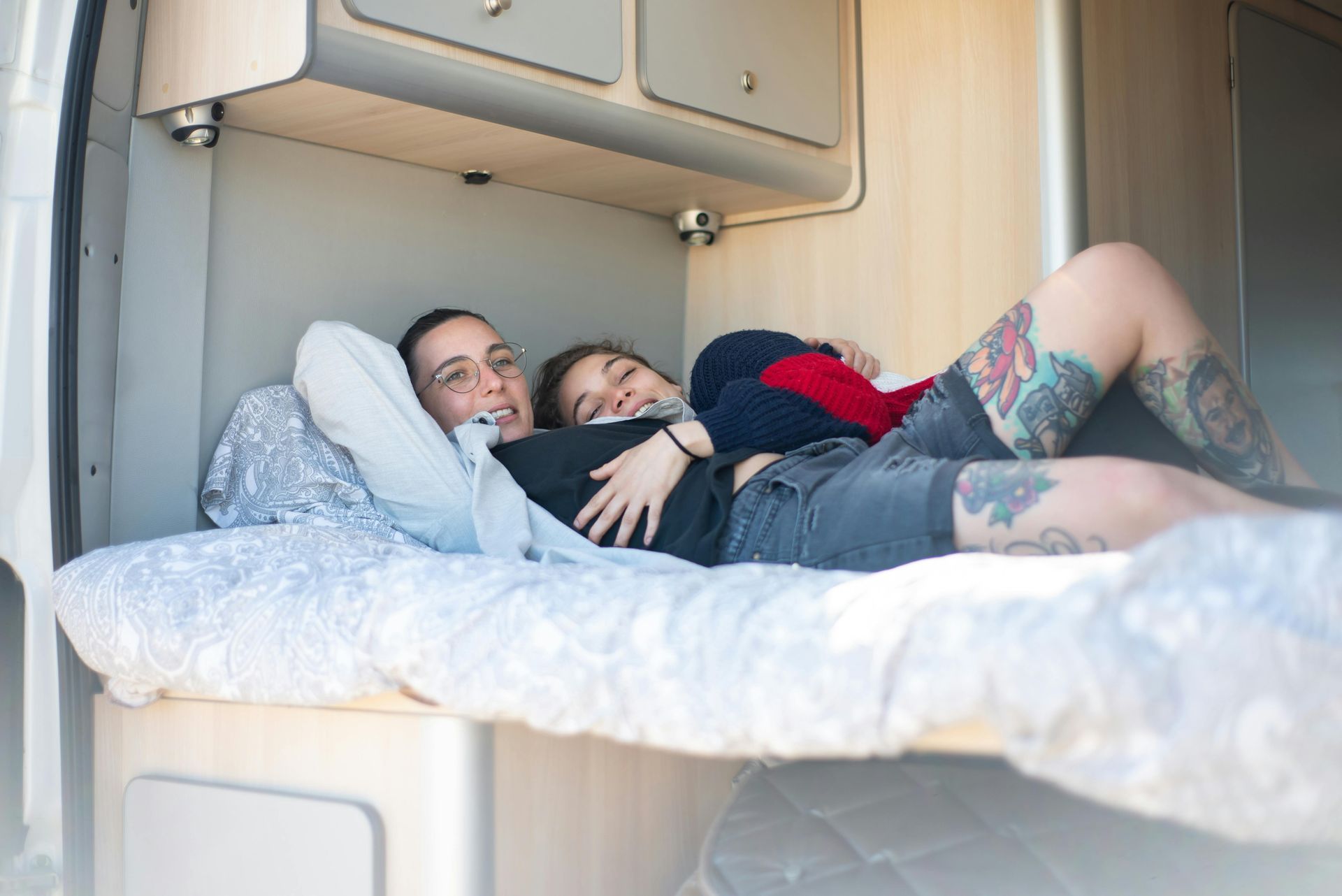 A man and a woman are laying on a bed in a van.