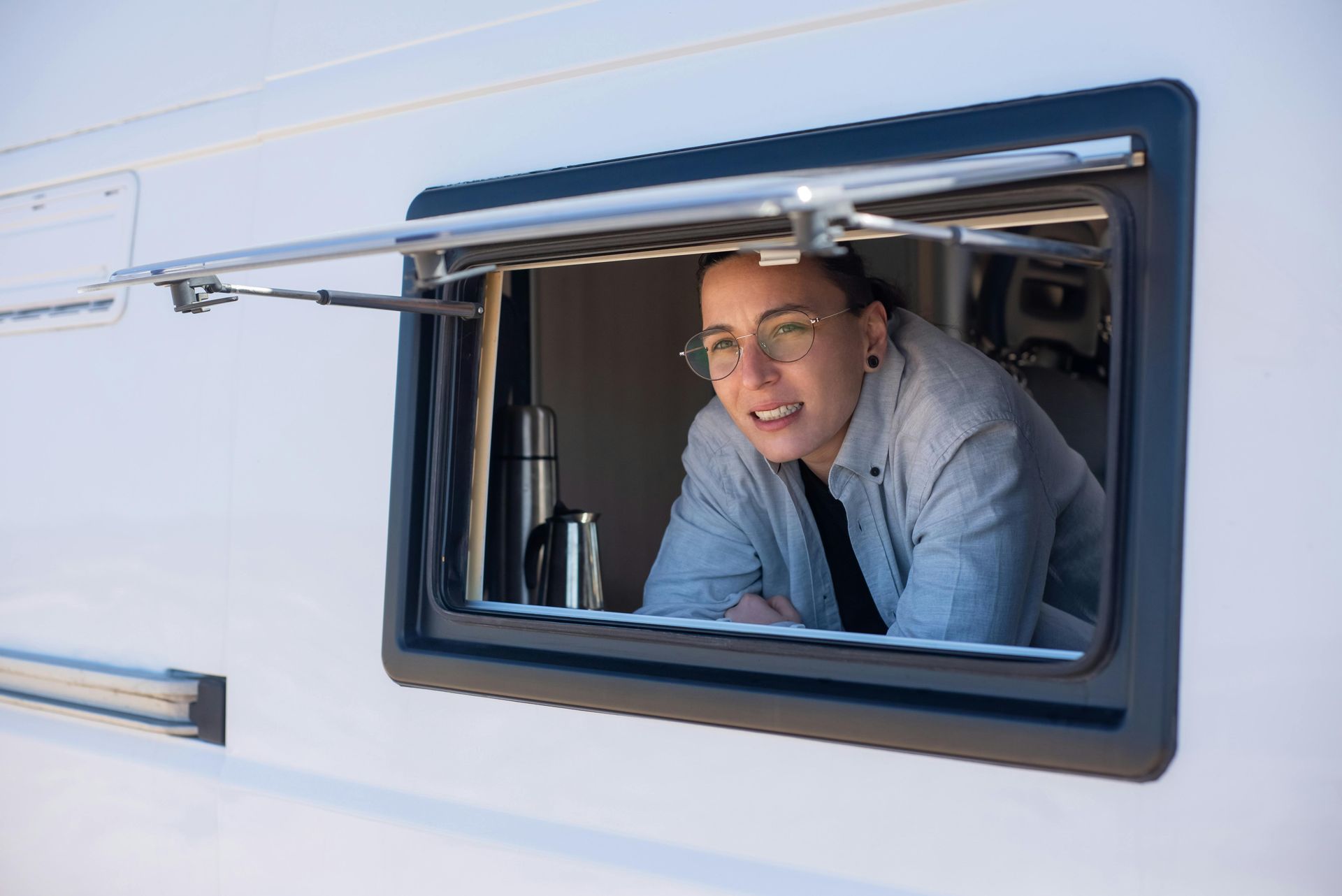 A woman is looking out of a window of a camper van.