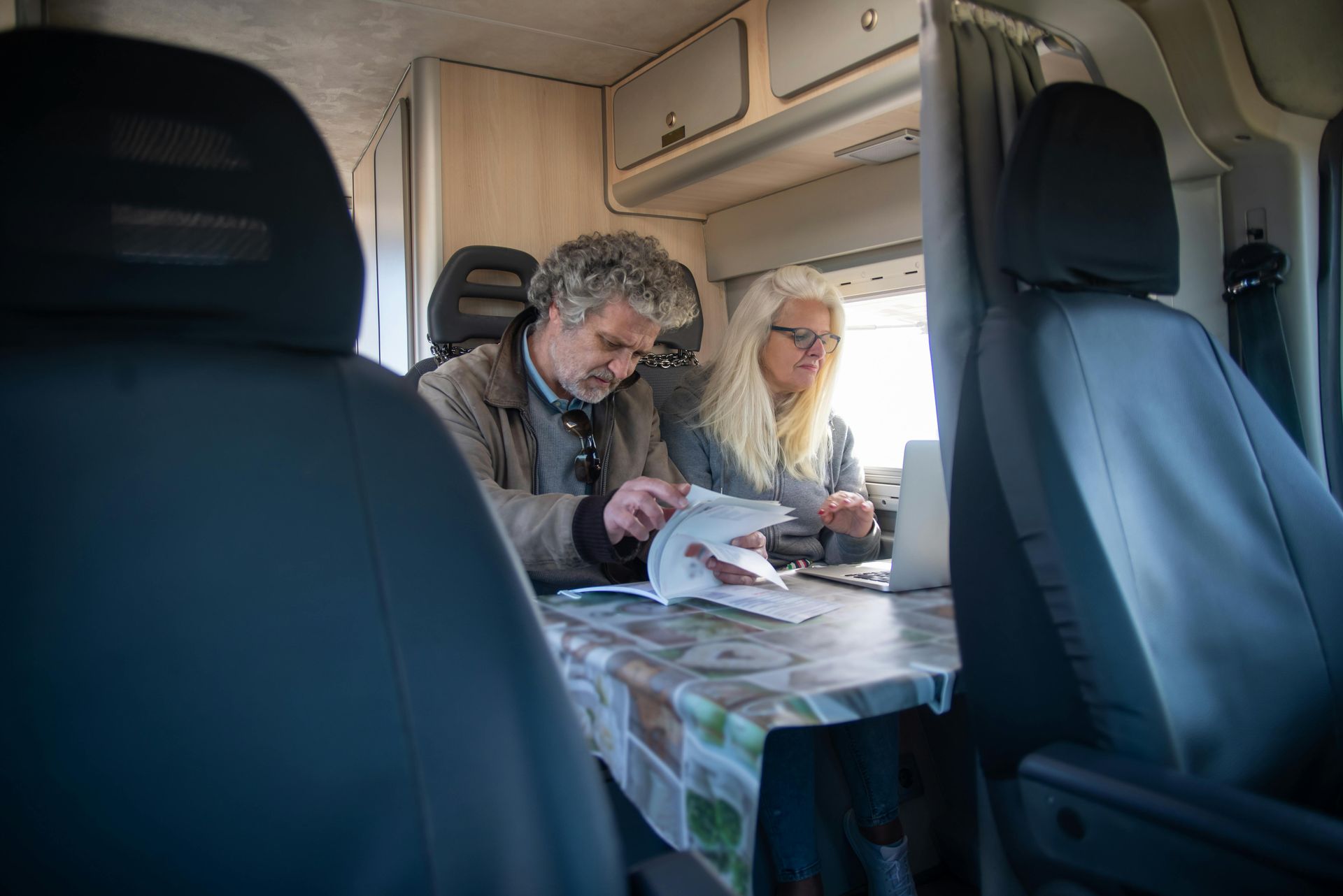 A man and a woman are sitting at a table in a camper van.